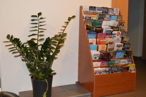 a book shelf filled with magazines next to a plant at HOTEL ARÉNA in Prague