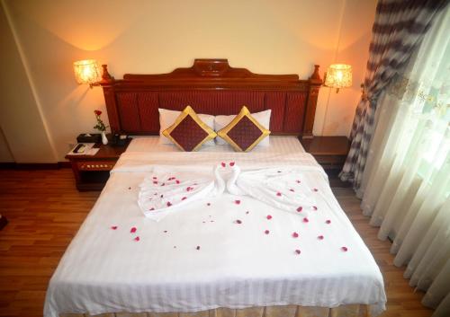 una cama con un vestido blanco y corazones rojos en ella en Central Hotel, en Quảng Ngãi