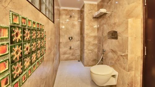 a bathroom with a toilet and a wall with paintings at Milestone 251 in Jaipur
