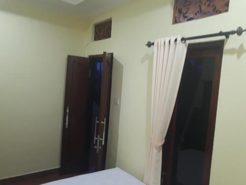 a bedroom with a bed and a closet and a curtain at Indy House in Ubud