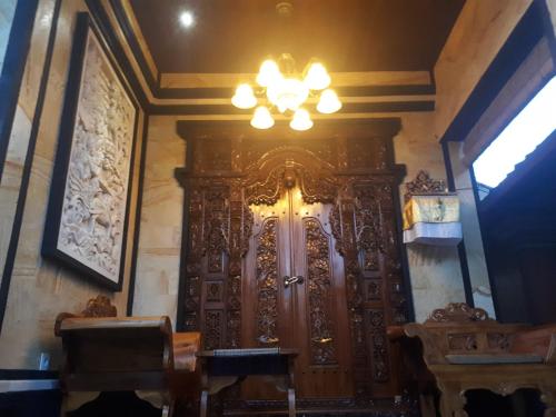 a large wooden door in a room with a chandelier at Indy House in Ubud