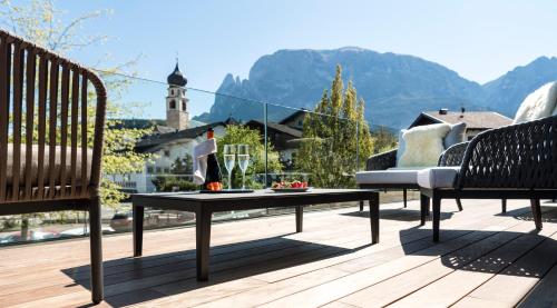 a patio with two benches and a table on a deck at Gartenhotel Völser Hof - Adults Only in Fiè