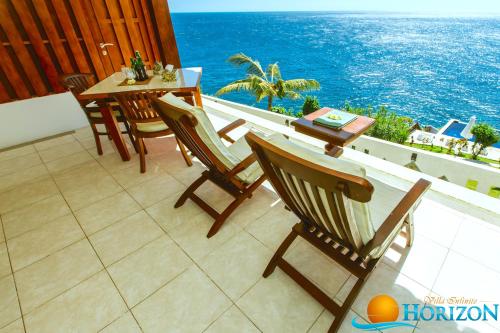 a balcony with a table and chairs and the ocean at Villa Infinite Horizon in Amed
