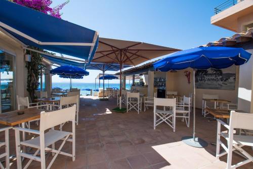 a restaurant with blue umbrellas and tables and chairs at Grand Hotel Moriaz in Le Lavandou