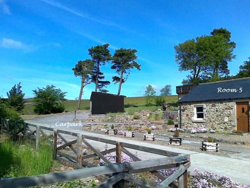 un edificio de piedra con una valla de madera al lado en Belle Vue Country, en Stanhope