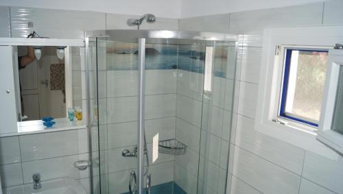 y baño con ducha y puerta de cristal. en Studios Vagos 1, en Agios Prokopios