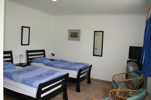 two beds in a room with a tv and chairs at Maggie´s Accommodation in Swakopmund