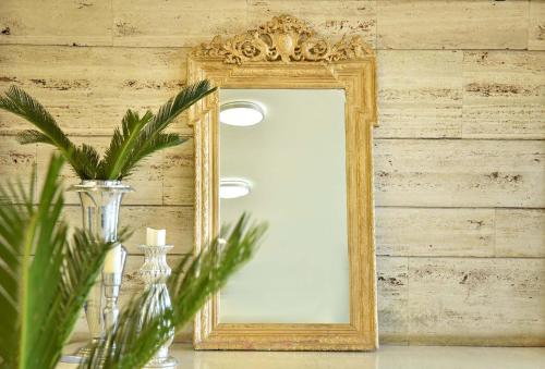 an ornate gold mirror on a wall with a vase at Ionion Star Hotel in Lefkada Town
