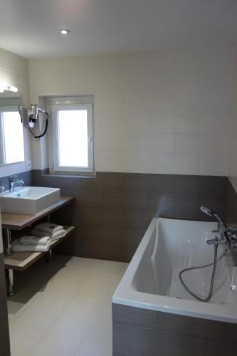 a bathroom with a large tub and a sink at Hotel le Préjoly in Saint-Vallier-de-Thiey