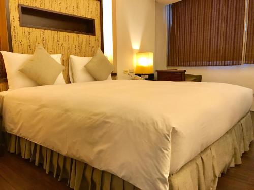 a large white bed in a hotel room at Shin Yuan Celeb Metro Hotel in Hsinchu City