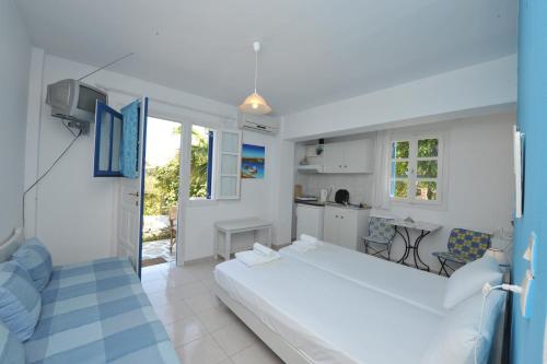 a white bedroom with a large bed and a kitchen at Pension Sofia Amorgos-Katapola in Katapola