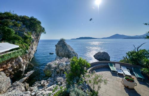 a view of the ocean from a cliff with benches at Kazanegra Exclusive Apartments in Sveti Stefan