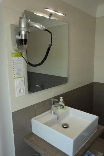 a bathroom with a white sink and a mirror at Hotel le Préjoly in Saint-Vallier-de-Thiey