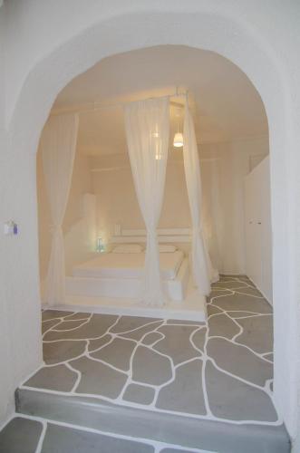 a white room with a bed with curtains in it at Olga in Ios Chora