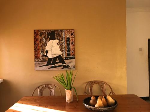 a dining room table with a painting on the wall at More Than A Drop in Moshi