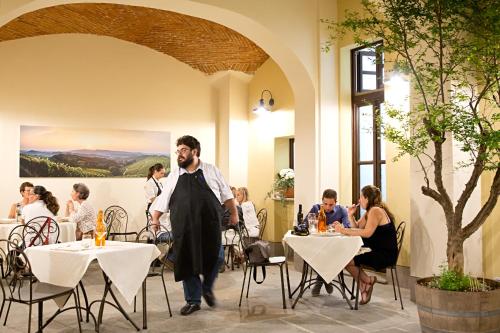 a man in an apron standing in a restaurant with tables at Osteria Senza Fretta Rooms for Rent in Cuneo