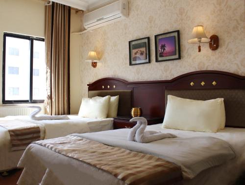 アンマンにあるRana Palaceのホテルルーム内のベッド2台(白鳥2羽付)