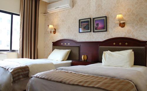 a hotel room with two beds and a window at Rana Palace in Amman