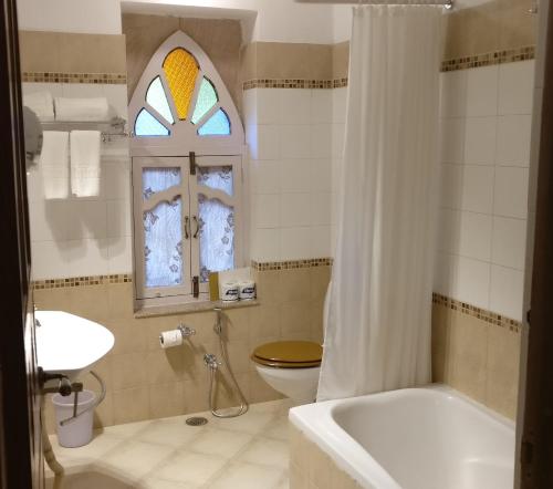 a bathroom with a tub and a toilet and a window at Welcomhotel by ITC Hotels, Fort & Dunes, Khimsar in Khinwasar