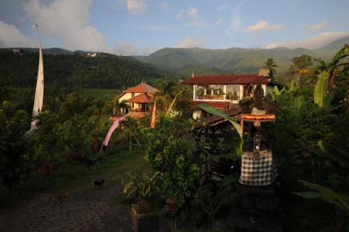 a house on a hill with mountains in the background at Lesong Hotel and Restaurant in Munduk