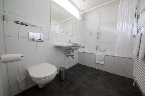 Baño blanco con aseo y lavamanos en Le Mont-Vully - Hôtel Restaurant en Haut-Vully