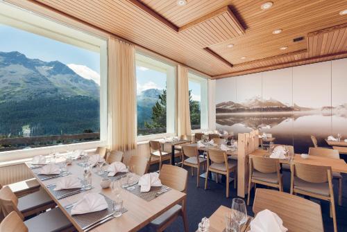 a restaurant with tables and chairs and large windows at Hostel by Randolins in St. Moritz