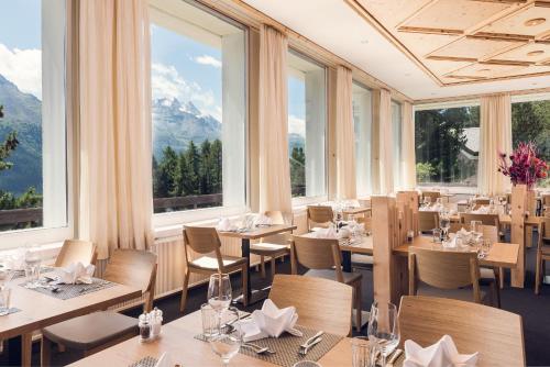 a restaurant with tables and chairs and large windows at Hostel by Randolins in St. Moritz