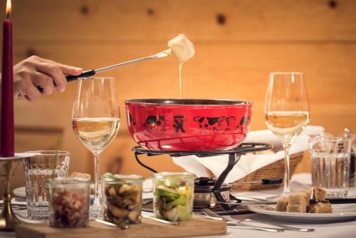 a person pouring wine into a red bowl on a table at Randolins Familienresort in St. Moritz