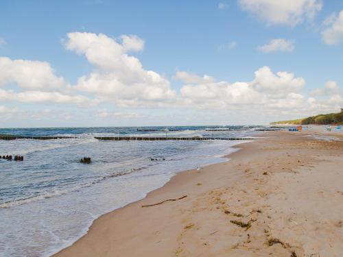 a sandy beach with a pier in the water at Apartament 59 Dwie Sosny in Ustronie Morskie