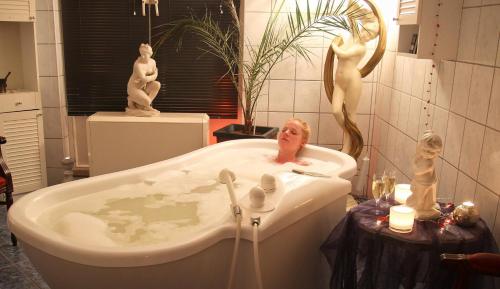 a bathroom with a bath tub with statues in it at Wellnesshotel Legde in Legde