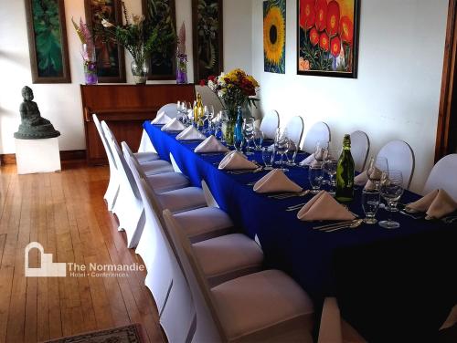 a long table with a blue table cloth and chairs at Hotel Normandie Limited in Port-of-Spain