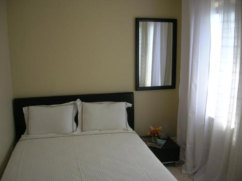 a bedroom with a bed with white pillows and a window at The Atrium Resort in Grace Bay