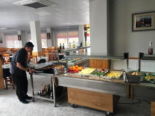 Hotel Ancla في أوروبيسا ديل مار: رجل يحضر الطعام في مطبخ المطعم