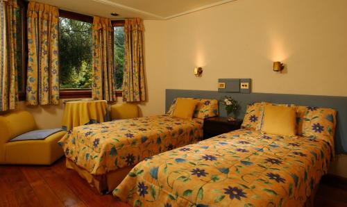a bedroom with two beds and a chair and a window at Hosteria Las Lengas by Visionnaire in San Martín de los Andes