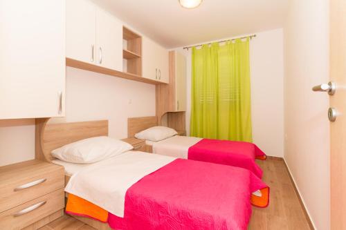 2 Betten in einem Zimmer mit grünem Vorhang in der Unterkunft Apartments Villa-Ines Center in Vodice