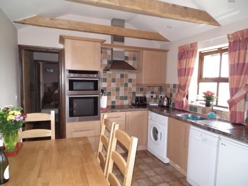 a kitchen with a table and a stove top oven at The Barn, Lower Spring in Tavistock