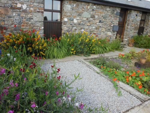 a garden with colorful flowers in front of a building at The Barn, Lower Spring in Tavistock