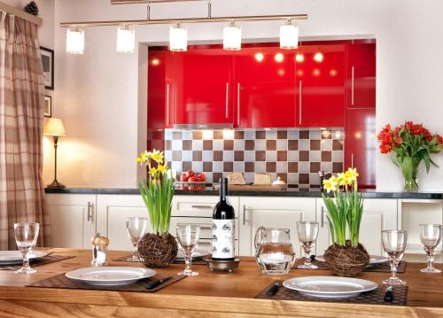a kitchen with red cabinets and a wooden table with wine glasses at Chalet Im Wieselti in Langwies