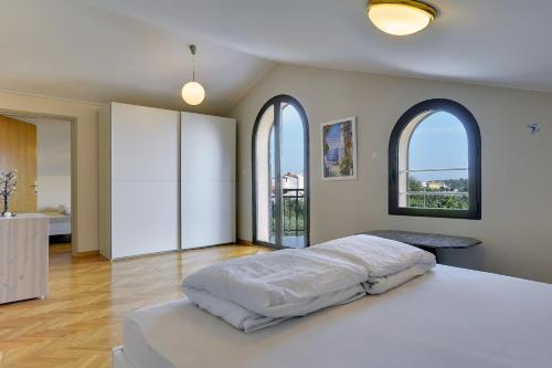 ein Schlafzimmer mit einem großen Bett und zwei Fenstern in der Unterkunft Villa Andrija Family Dream with heating pool at the sea in Fažana