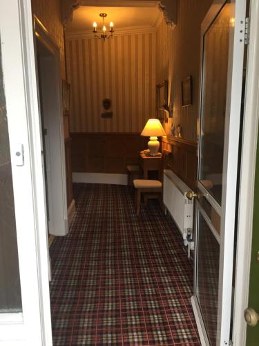 a hallway with a room with a table and a lamp at The Ivy House Ferry Link in Stranraer