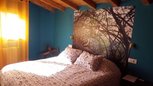 a bedroom with a bed with a tree mural on the wall at Casa Rural El Peral in Caminomorisco
