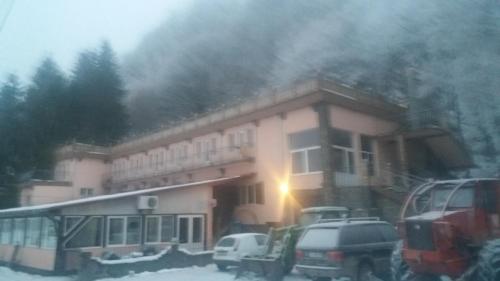a building with cars parked in front of it at Complex Turistic Gura Jgheabului in Oţelu Roşu