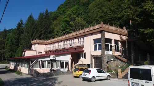 a building with two cars parked in front of it at Complex Turistic Gura Jgheabului in Oţelu Roşu