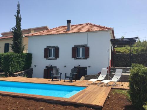 a house with a wooden deck and a swimming pool at Casa das Marias in Ponta do Pargo