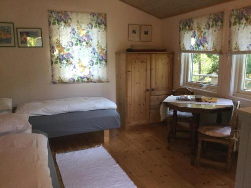 a bedroom with a bed and a table and windows at Lillstuga Strömma in Värmdö