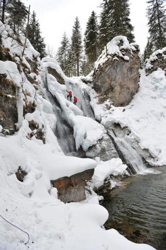 a snow covered waterfall next to a body of water at Haus Loferer in Sankt Martin bei Lofer