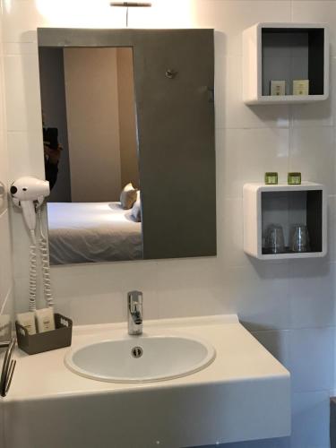 a bathroom with a sink and a mirror and a bed at Hotel Spa Le Relais Des Moines in Villersexel