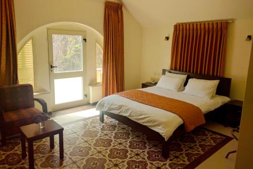 a bedroom with a bed and a chair and a window at Alhambra Palace Hotel Suites - Ramallah in Ramallah