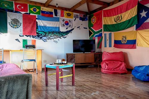 una sala de estar con banderas en la pared y una mesa en Hostel Los Cormoranes en Ushuaia