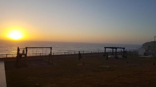 a sunset over the ocean with a playground at Hotel Apartamento Praia Azul in Santa Cruz
